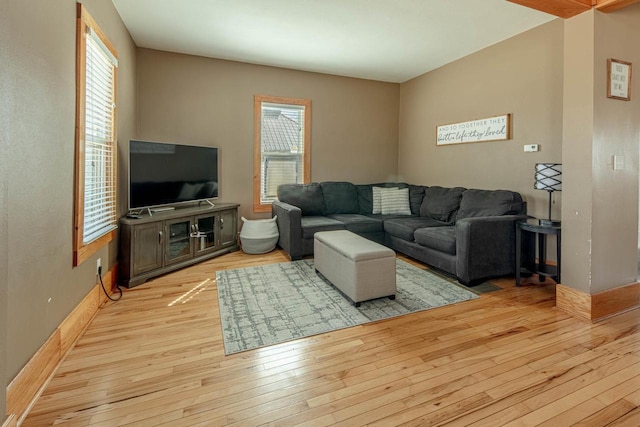 living room featuring light wood-type flooring, plenty of natural light, and baseboards