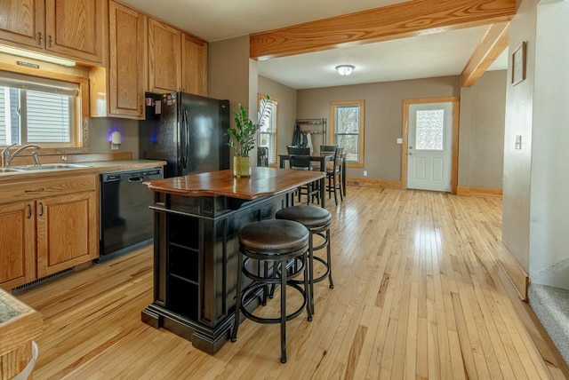 kitchen featuring black appliances, light wood-style floors, baseboards, and a sink