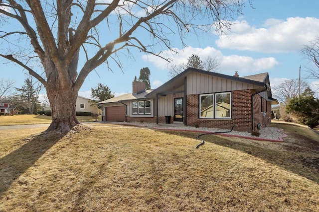 view of front of property featuring a front yard, brick siding, a chimney, a garage, and board and batten siding