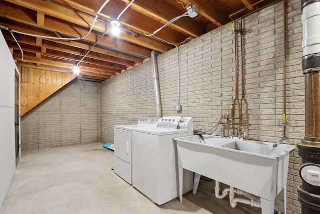 laundry area with a sink, brick wall, washing machine and dryer, and laundry area