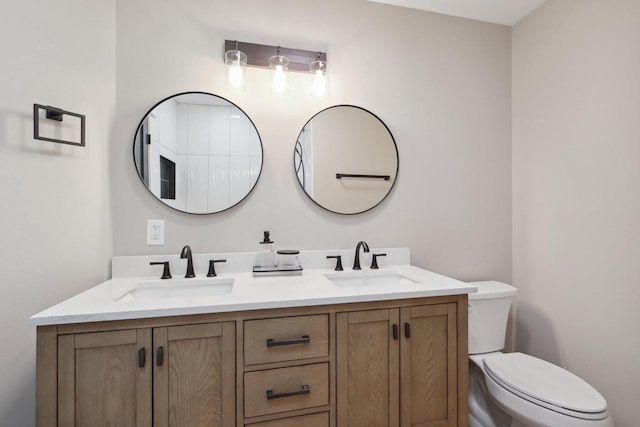 bathroom with a sink, toilet, and double vanity