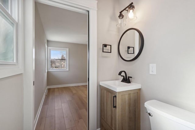 bathroom featuring vanity, toilet, wood finished floors, and baseboards