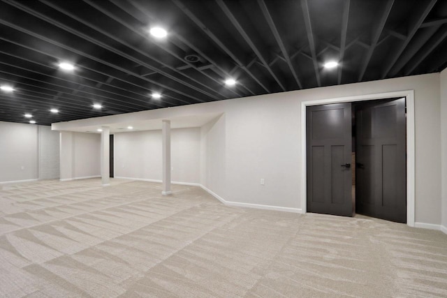 finished basement featuring baseboards and light carpet