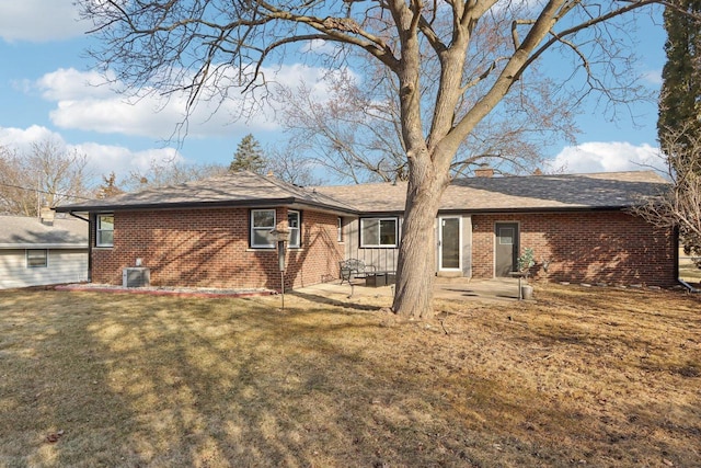 back of house featuring a lawn, central AC, brick siding, a chimney, and a patio area