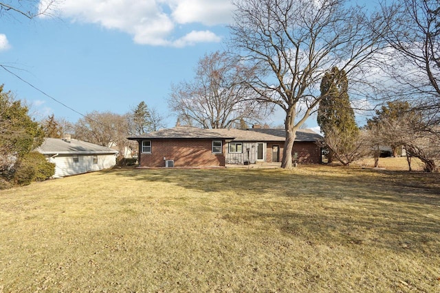 rear view of property with brick siding and a lawn