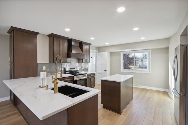 kitchen with light wood finished floors, backsplash, premium range hood, and appliances with stainless steel finishes