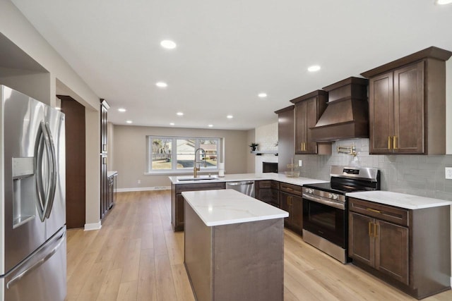 kitchen featuring premium range hood, decorative backsplash, a peninsula, stainless steel appliances, and a sink