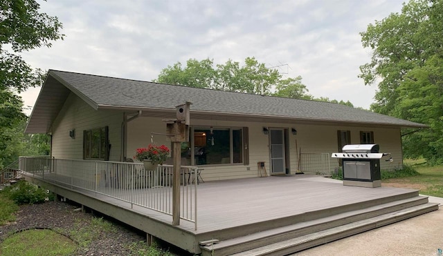 back of house with a wooden deck and roof with shingles