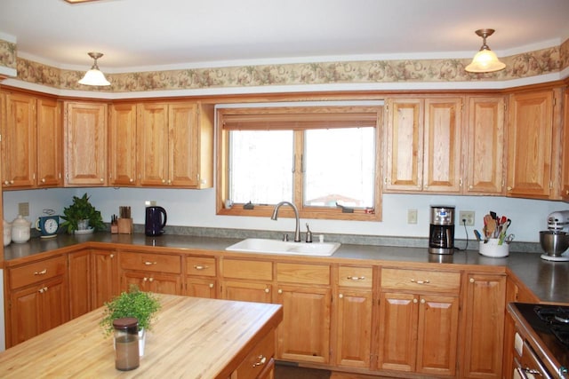 kitchen featuring a sink, wooden counters, brown cabinets, and hanging light fixtures