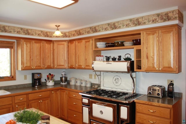 kitchen with gas range oven, range hood, dark countertops, and brown cabinets