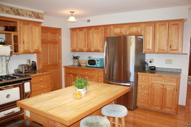 kitchen featuring visible vents, light wood-style flooring, wood counters, freestanding refrigerator, and white microwave