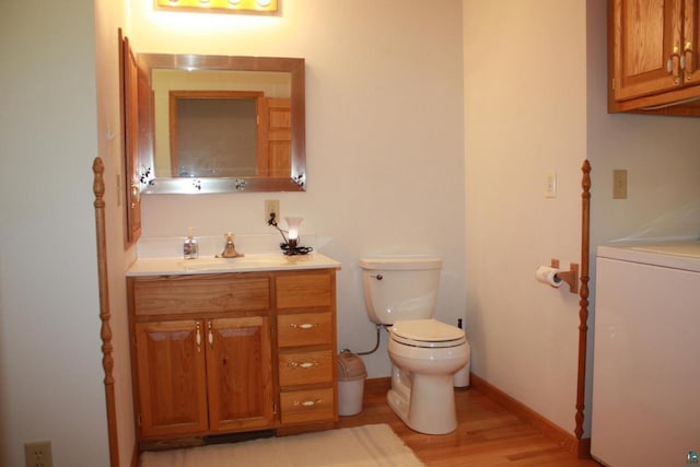 half bath featuring baseboards, toilet, washer / dryer, wood finished floors, and vanity