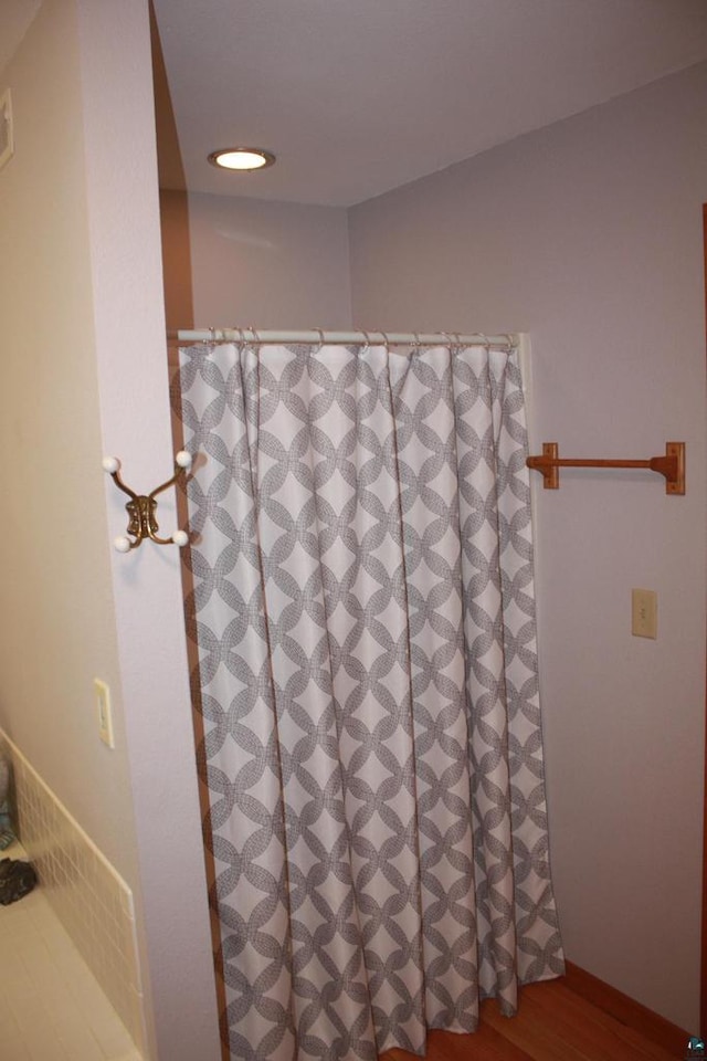 full bathroom with curtained shower and wood finished floors