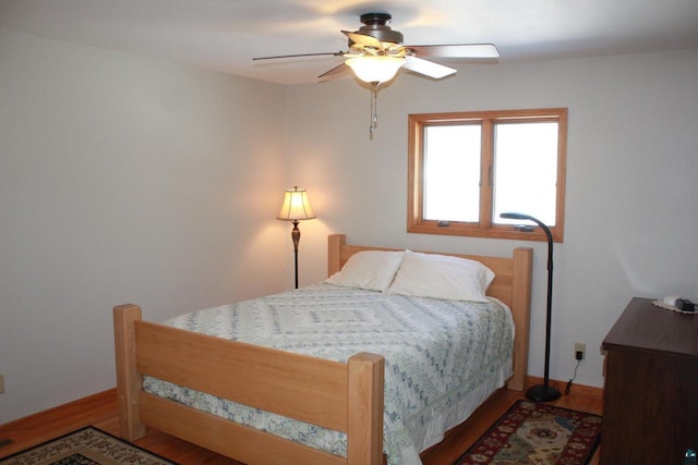 bedroom featuring baseboards, wood finished floors, and a ceiling fan