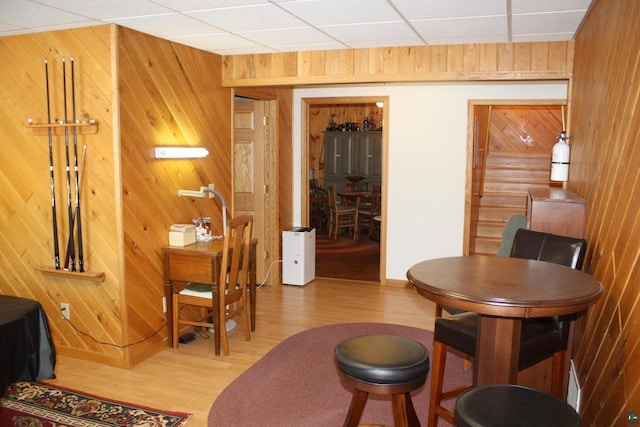 living area featuring wood walls, a paneled ceiling, and wood finished floors