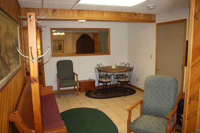 living area featuring tile patterned flooring, baseboards, and a drop ceiling