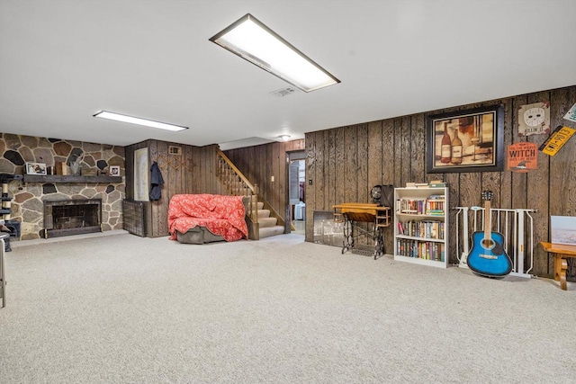 game room with visible vents, carpet floors, a stone fireplace, and wood walls