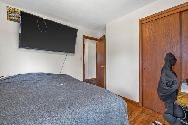 bedroom featuring a closet, wood-type flooring, and baseboards