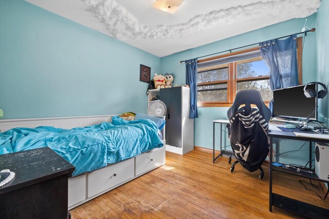 bedroom with hardwood / wood-style flooring and wainscoting