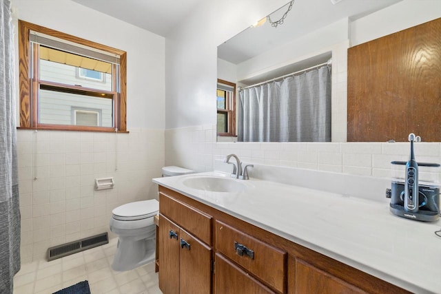 full bath featuring visible vents, toilet, tile walls, wainscoting, and vanity