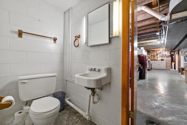 half bath with toilet, concrete floors, and concrete block wall