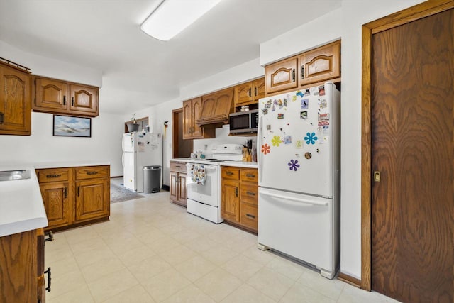 kitchen with white appliances, brown cabinetry, and light countertops