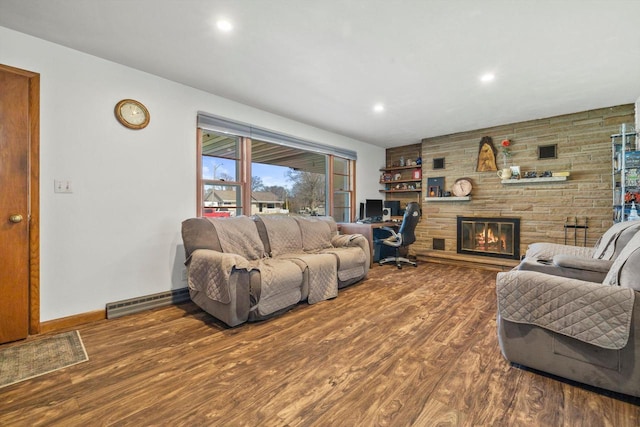 living room featuring wooden walls, baseboards, a stone fireplace, recessed lighting, and wood finished floors