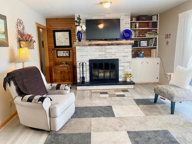 living room with a fireplace, baseboards, and wood finished floors