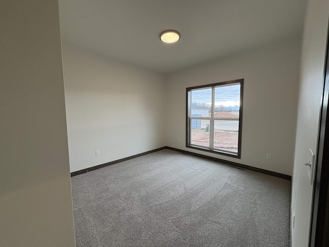 carpeted spare room featuring baseboards