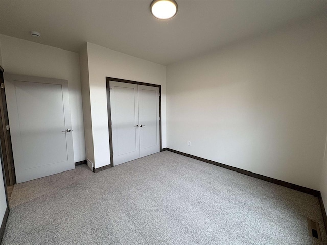 unfurnished bedroom featuring baseboards, visible vents, a closet, and carpet