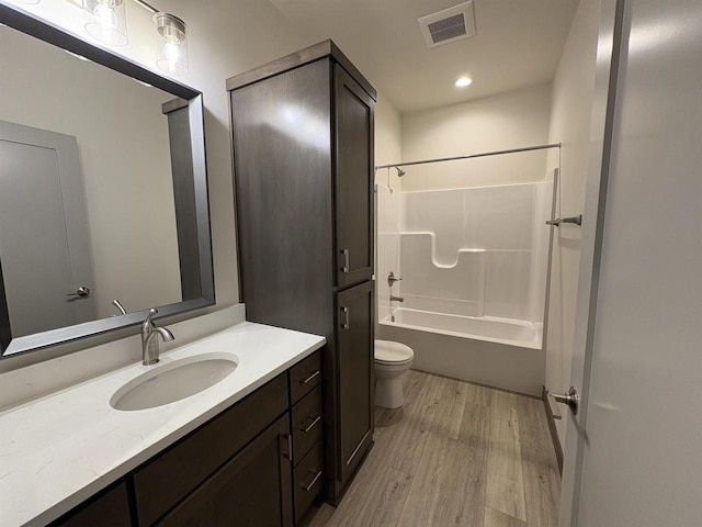 full bath featuring visible vents, toilet, wood finished floors, vanity, and shower / tub combination
