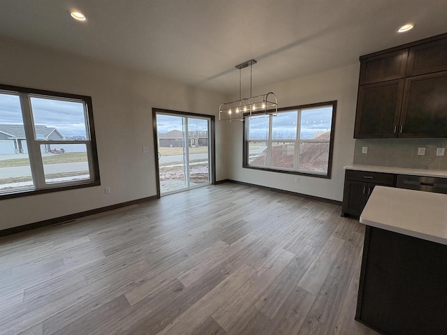 unfurnished dining area featuring baseboards, a chandelier, recessed lighting, and light wood-type flooring