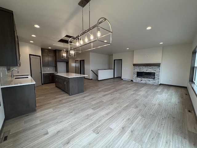 kitchen with light countertops, light wood-style flooring, recessed lighting, a kitchen island, and a sink