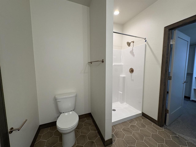 bathroom featuring baseboards, toilet, and a stall shower