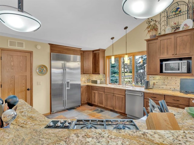 kitchen featuring visible vents, a sink, stainless steel appliances, brown cabinetry, and vaulted ceiling