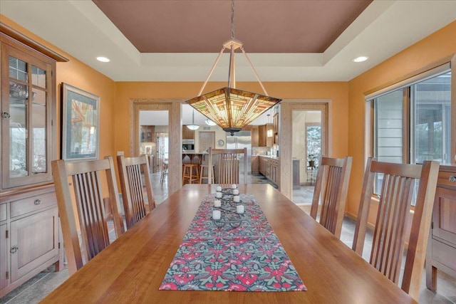 dining space with a raised ceiling and recessed lighting