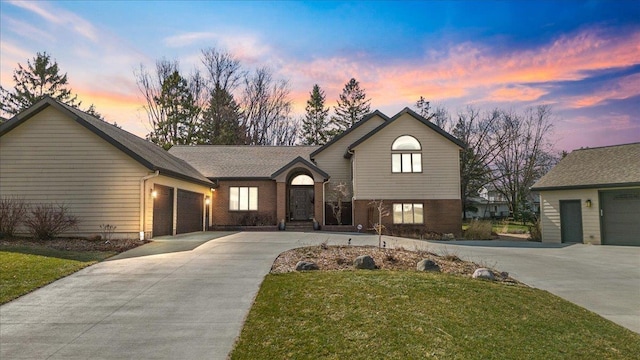 split level home with brick siding, a yard, concrete driveway, and a garage