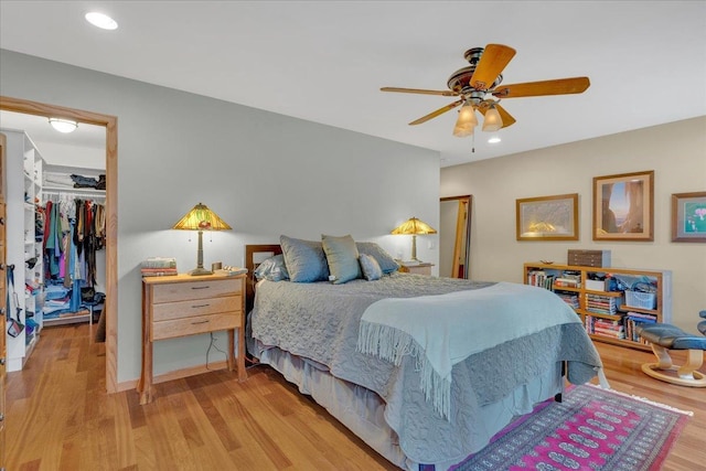 bedroom with a spacious closet, recessed lighting, light wood-style flooring, and a closet