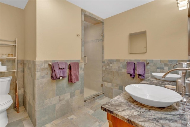 full bath featuring a wainscoted wall, toilet, tile walls, a shower stall, and vanity