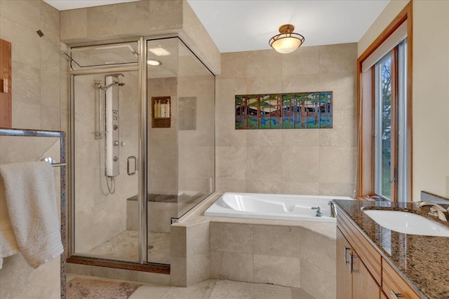 bathroom with a garden tub, tile walls, a stall shower, and vanity