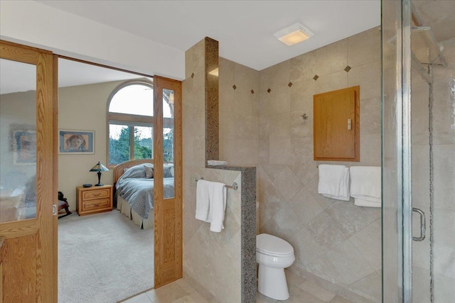 bathroom with toilet, tile walls, a stall shower, and tile patterned flooring