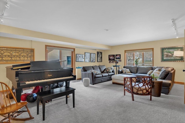 carpeted living room featuring track lighting and baseboards