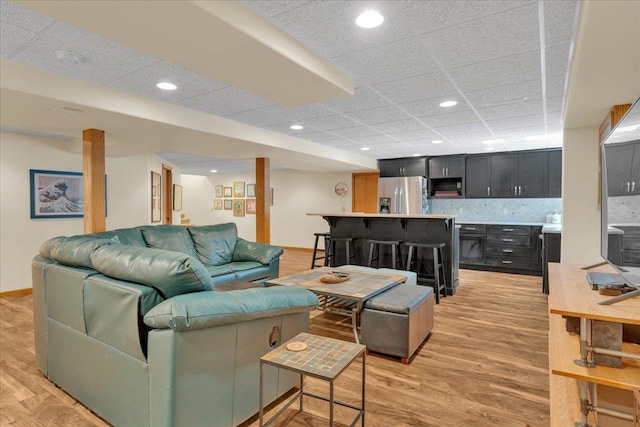 living area featuring recessed lighting, a drop ceiling, baseboards, and light wood-style floors