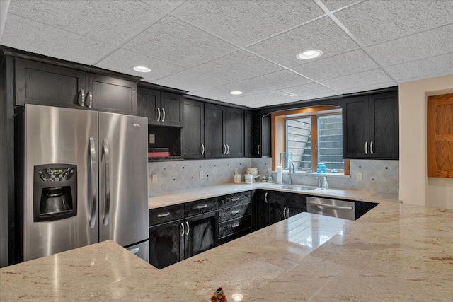 kitchen with a sink, dark cabinetry, light stone countertops, and stainless steel appliances