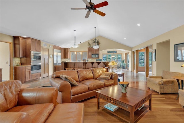 living room with light wood-type flooring, a ceiling fan, recessed lighting, arched walkways, and lofted ceiling