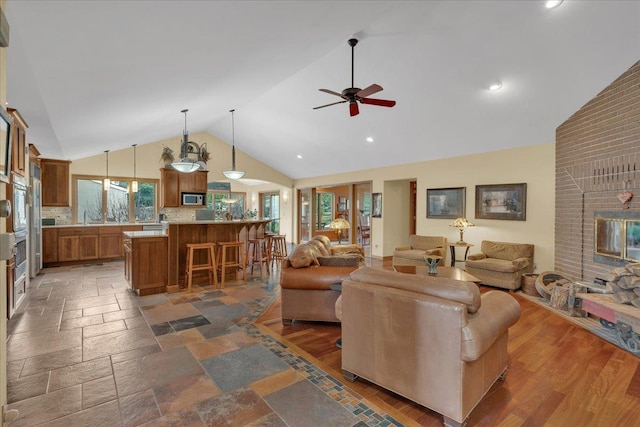 living area featuring ceiling fan, high vaulted ceiling, stone tile flooring, and recessed lighting