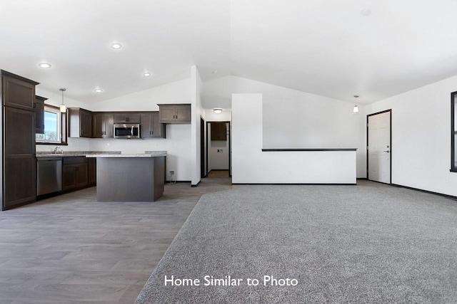 kitchen featuring a center island, dark brown cabinetry, light countertops, vaulted ceiling, and stainless steel appliances