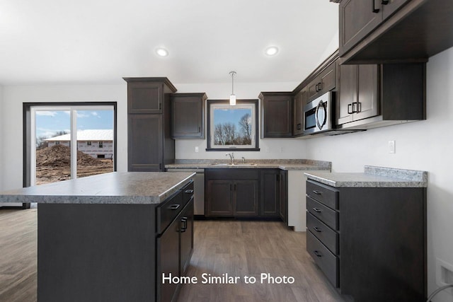 kitchen with light wood-style flooring, recessed lighting, stainless steel appliances, dark brown cabinetry, and a center island