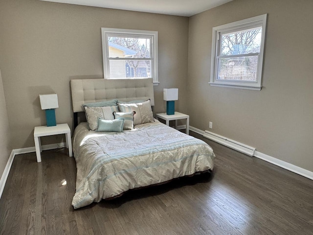 bedroom featuring a baseboard heating unit, wood finished floors, and baseboards