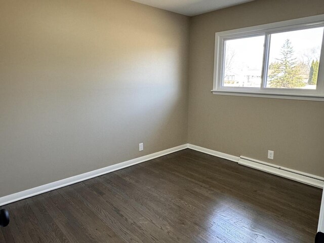 unfurnished room featuring a baseboard radiator, baseboards, and dark wood-type flooring